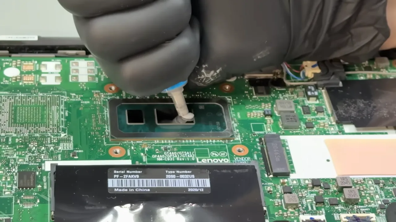 A person applying new thermal paste on CPU die on laptop.