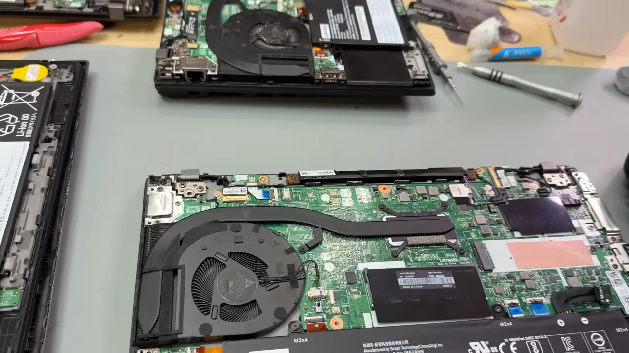 Laptop bottom panel removed showing fan and heat sink fins inside.