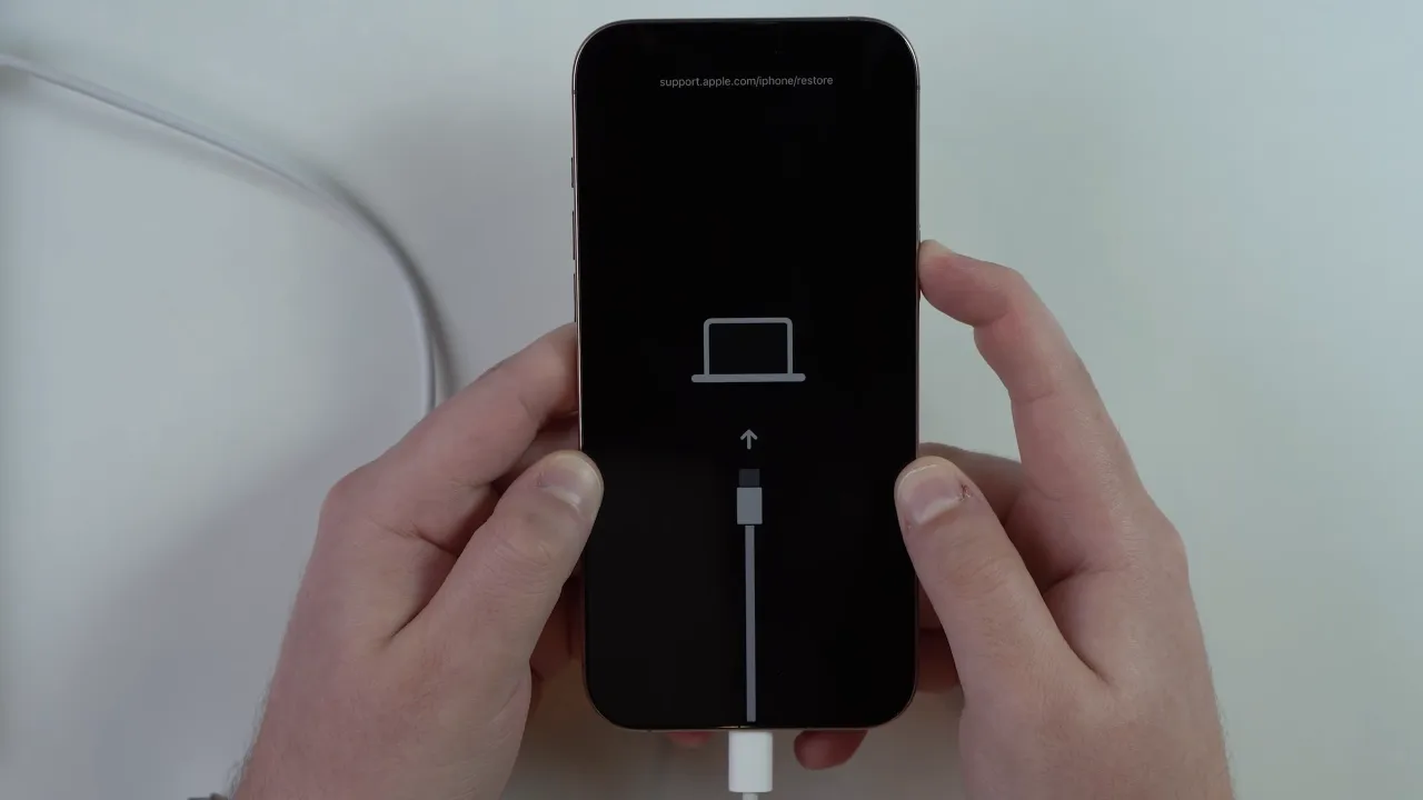 A person pressing and holding buttons to enter Recovery Mode on iPhone.