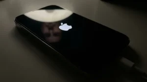 Close-up photograph of an iPhone 14 Pro screen displaying a stuck Apple logo on a black background.